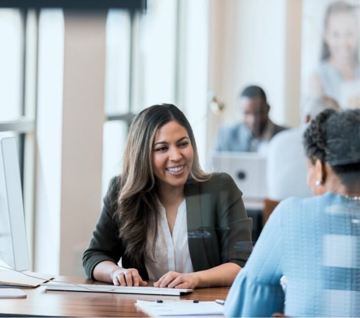 Bank relationship manager smiling with colleagues in an open plan office, illustrating UAE corporate bank account opening