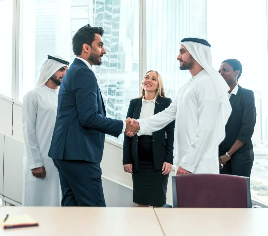 Emirati and international business people shaking hands in a Dubai meeting room, illustrating investment opportunities