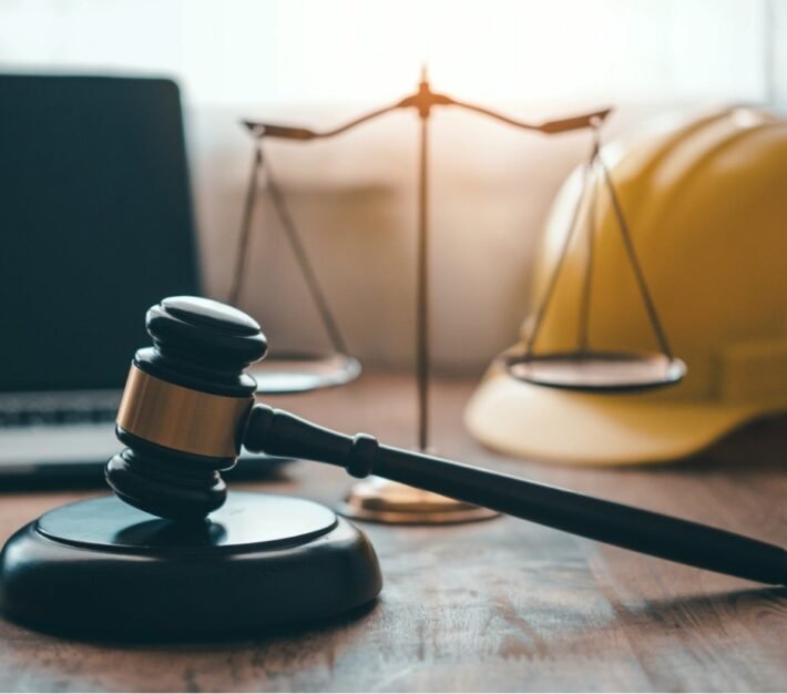 Gavel and scales of justice beside a hard hat and laptop, illustrating past and present UAE labour law