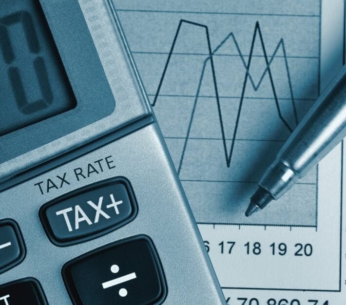 Calculator showing a tax key beside financial charts, illustrating the UAE tax registration number