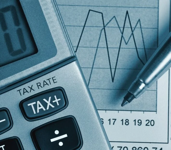 Calculator showing a tax key beside financial charts, illustrating the UAE tax registration number