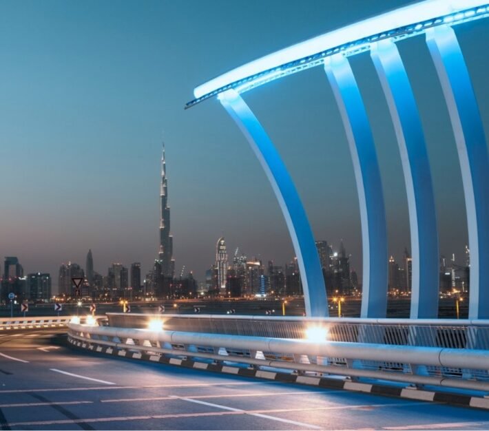 Illuminated Dubai Water Canal bridge with the city skyline behind, illustrating Meydan Free Zone