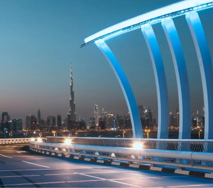 Illuminated Dubai Water Canal bridge with the city skyline behind, illustrating Meydan Free Zone