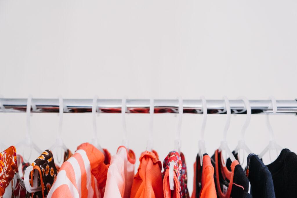 Circular Economy, Second hand, Fast fashion, Sustainable fashion. Many second hand red colors clothes hanged on clothes rack.