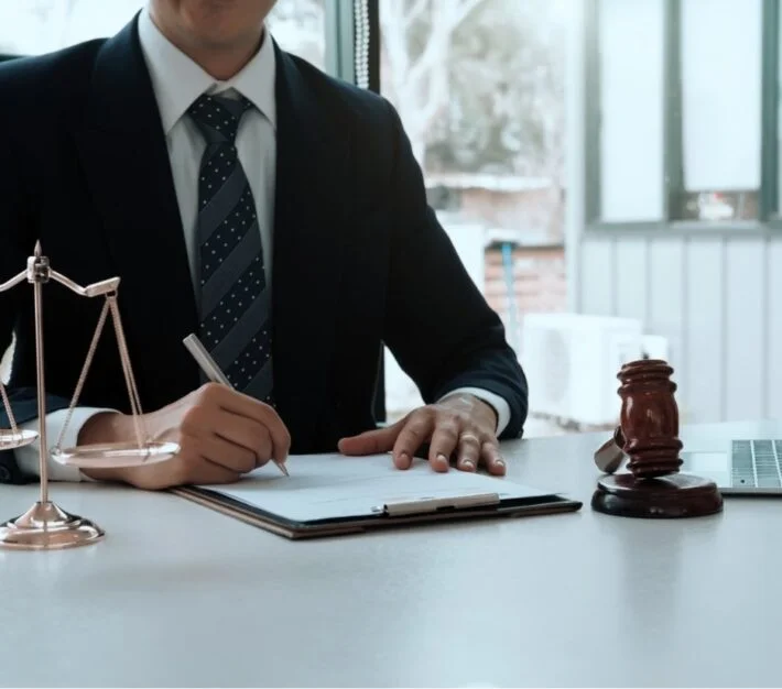 Lawyer signing documents beside scales of justice and a gavel, illustrating UAE succession under Sharia and common law