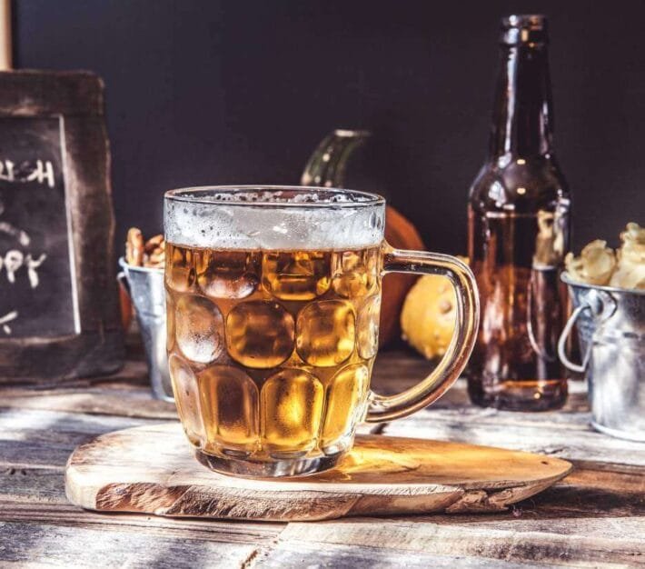 Glass of beer and bottles on a wooden table, illustrating the Dubai liquor licence